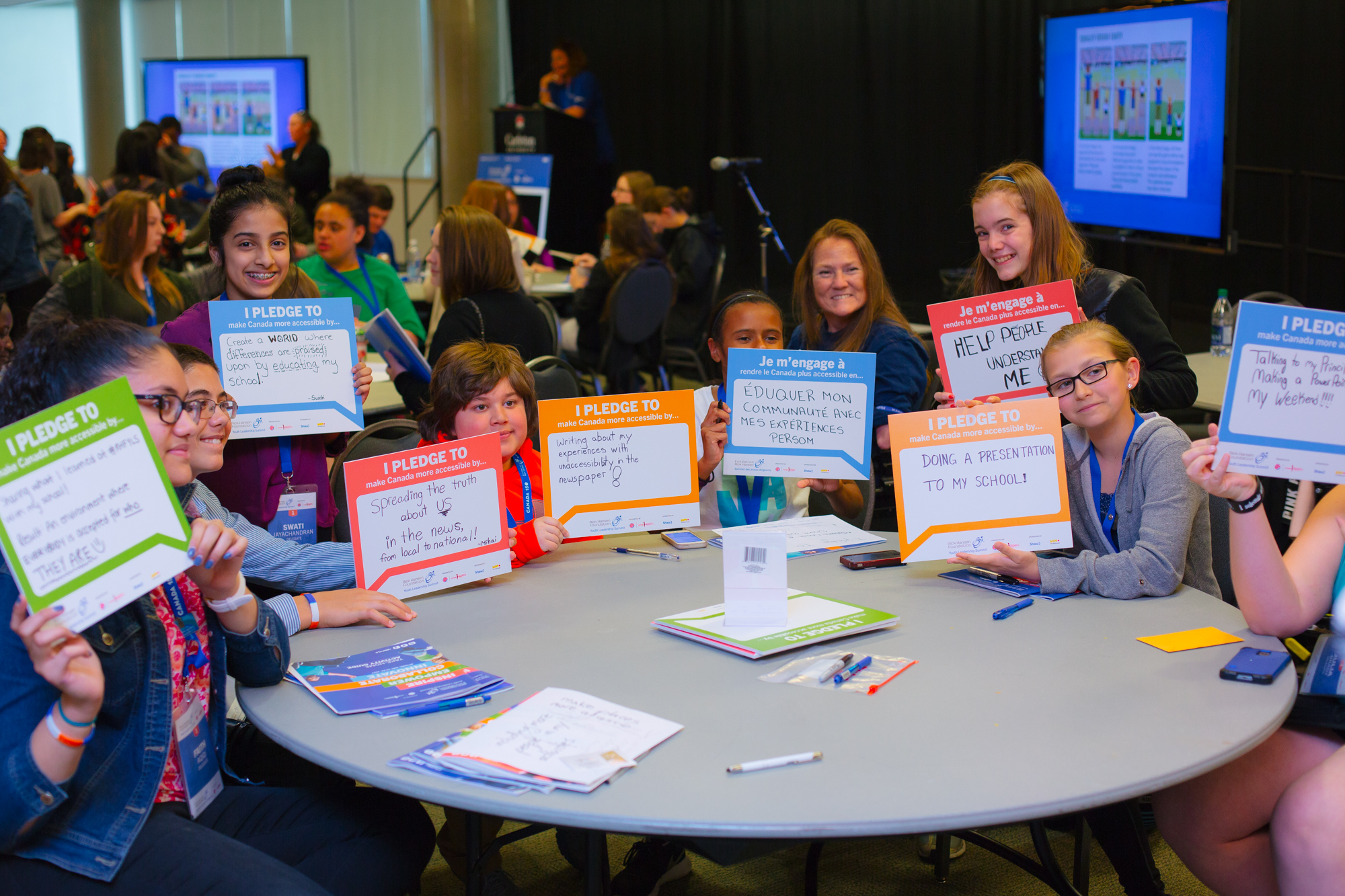 Picture of eight children who joined the Youth Summit. Each of them is holding a paper where they wrote their pledge to improve the accessibility and inclusion.